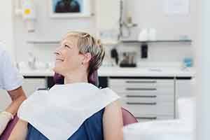 Female patient in chair smiling at her dentist