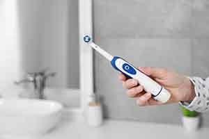 Close-up of woman’s hand holding an electric toothbrush